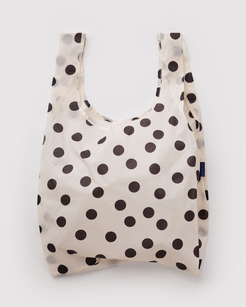 A reusable plastic shopping bag with a cream background and dark brown polka dots, shown against a light gray background.