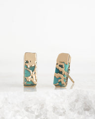 Pair of gold and turquoise earrings on a white background
