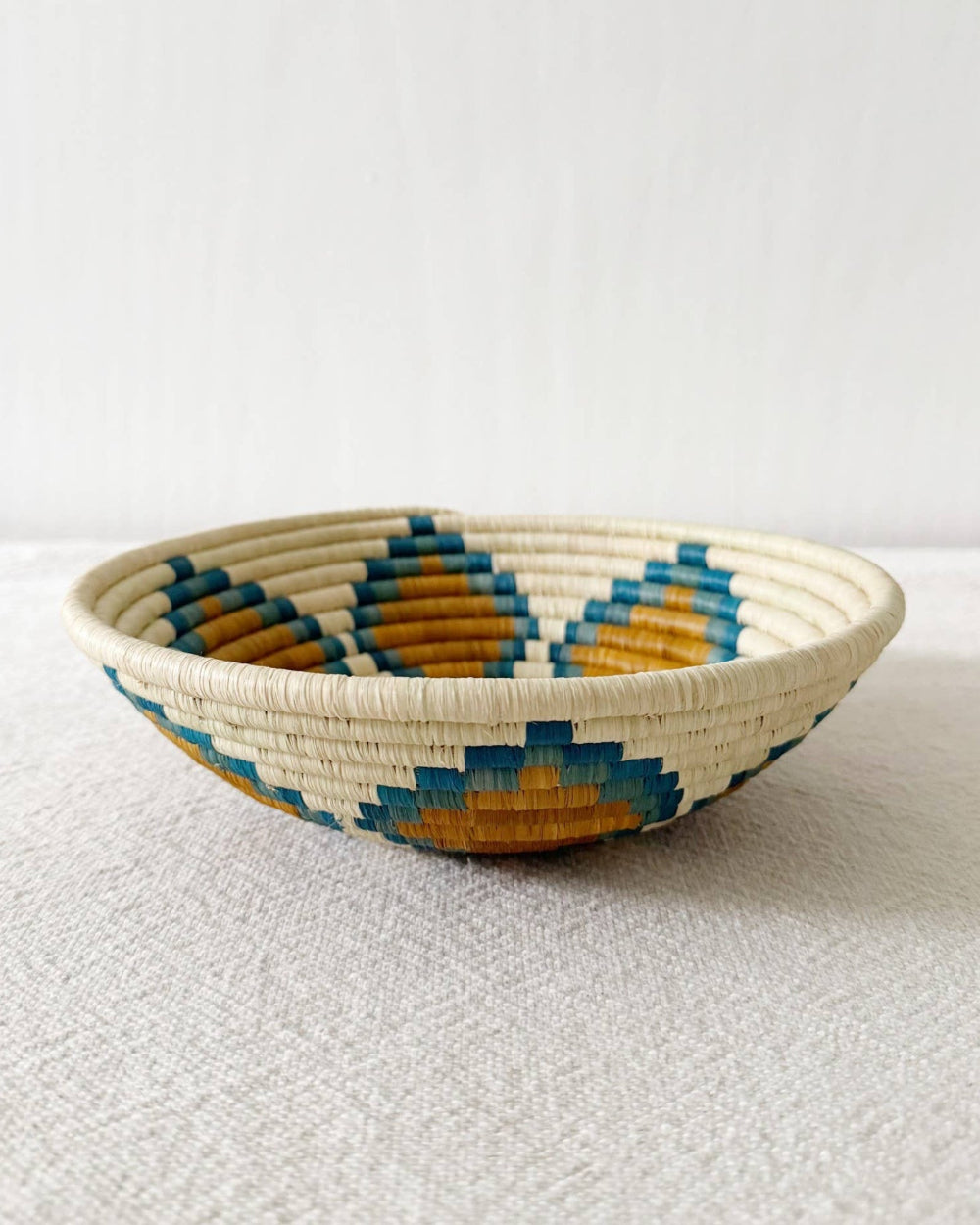 Woven bowl with blue and orange pattern on a white background