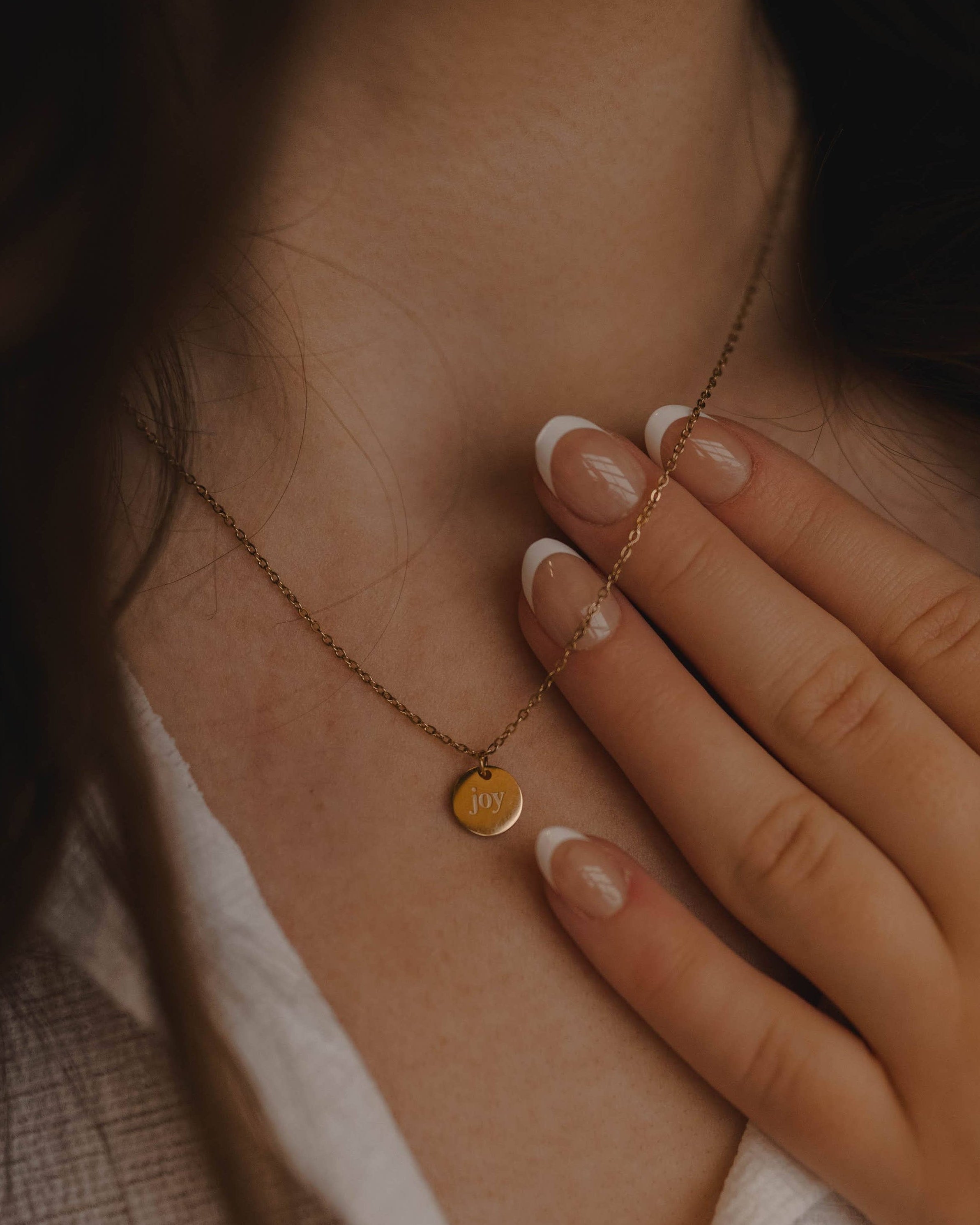 Close-up of a necklace with a round pendant worn by a person.
