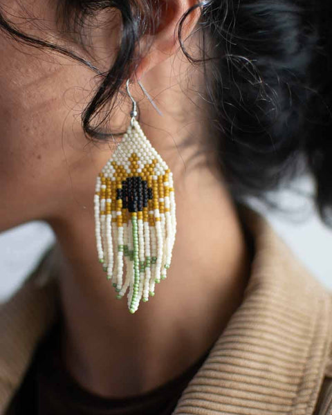 Close-up of a person wearing sunflower-themed beaded earrings.
