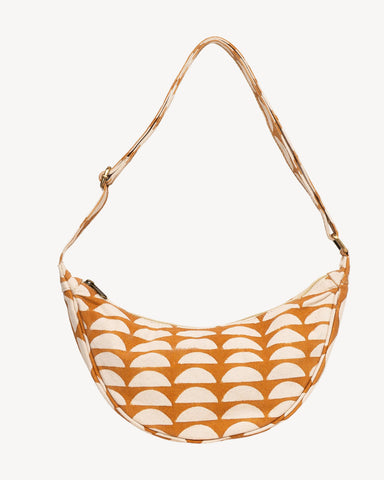 Close-up of an open zip pouch showing a warm orange-brown interior lining and a patterned exterior with white leaf-like shapes on a mustard-brown base.