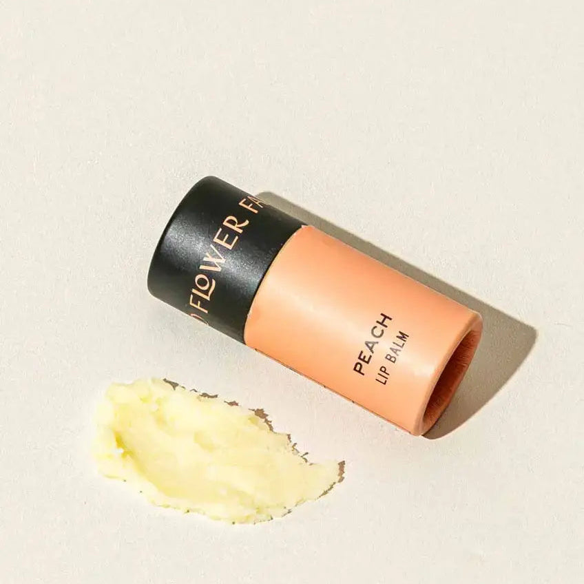 Flower Beauty peach lip balm on a beige background