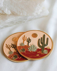 Coasters with cactus design on a white surface with glasses of pink drink.