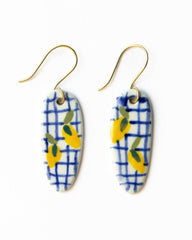 Pair of earrings with blue and white checkered pattern and yellow accents on a white background