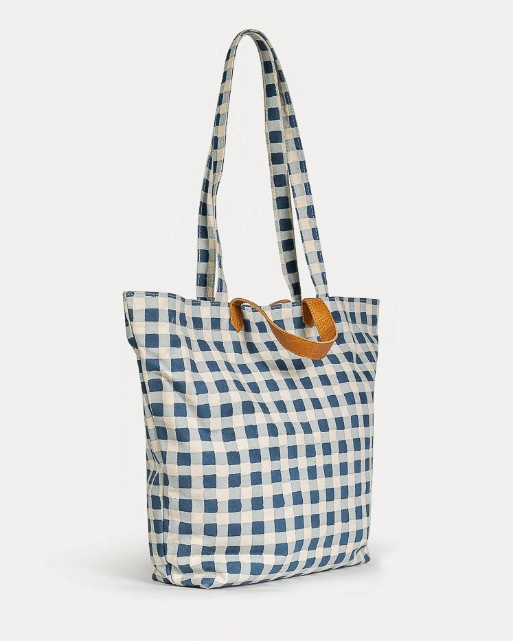 Blue and white checkered tote bag with a brown handle on a light gray background