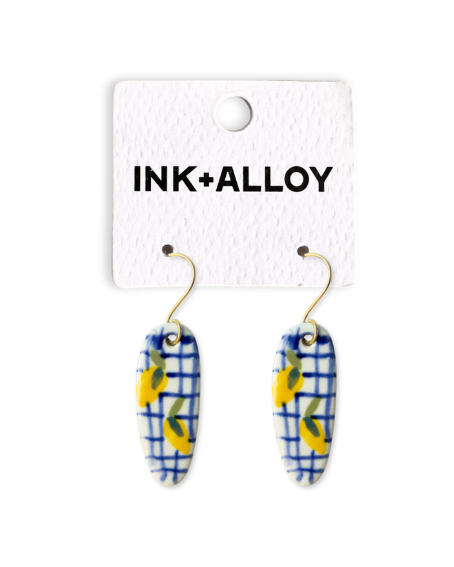 Pair of earrings on a 'INK+ALLOY' branded card against a white background