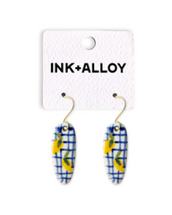 Pair of earrings on a 'INK+ALLOY' branded card against a white background