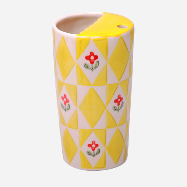 Cylindrical ceramic vase with yellow diamond pattern and red floral design on a white background