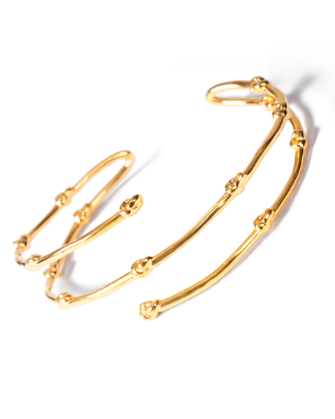 A gold-toned open cuff bracelet with a textured, branch-like segmented design, photographed on a clean white background with a soft shadow.