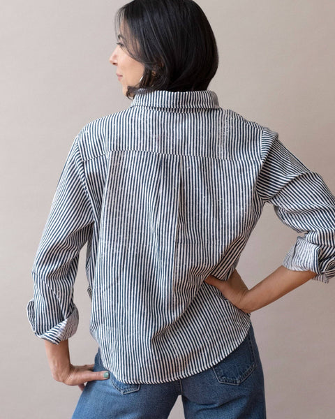 Person wearing a striped shirt and jeans against a plain background