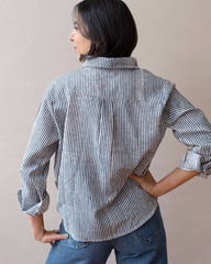 Person wearing a striped shirt and jeans against a plain background