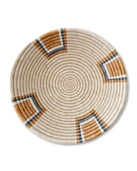 A round woven basket or tray with a spiral pattern in natural beige, brown, and navy blue on a white background.