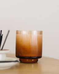 Brown glass candle holder on a wooden surface with a blurred background