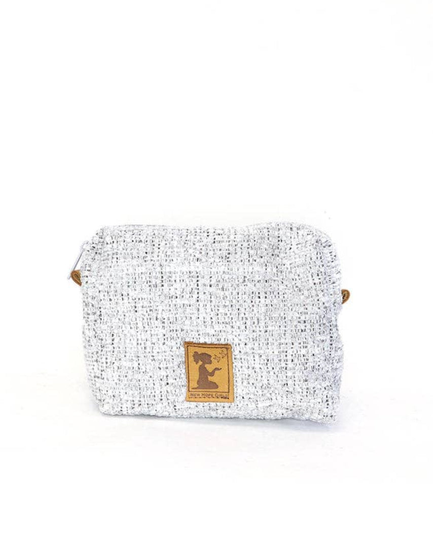 A small woven pouch or cosmetic bag in a light gray and white textured tweed fabric, featuring a small gold-tone metal logo plaque on the front and a tiny gold accent on the side, set against a plain white background.