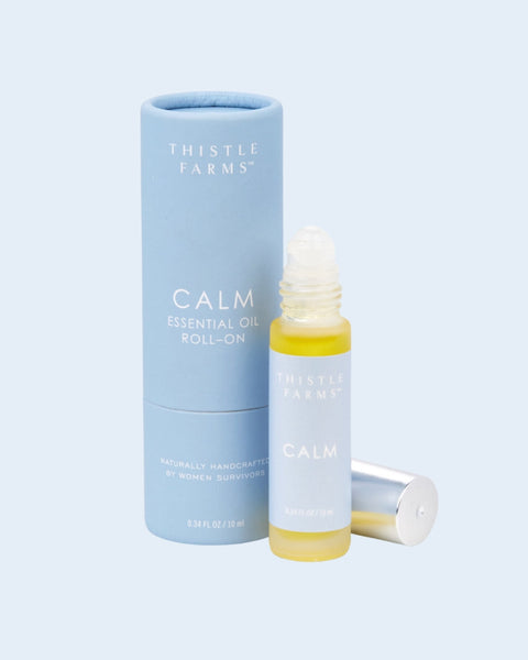 Thistle Farms Calm essential oil roll-on bottle and packaging on a light blue background