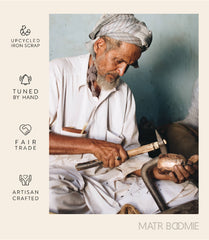 Man working with tools, surrounded by 'upcycled iron scrap', 'tuned by hand', 'fair trade', and 'artisan crafted' labels, with 'Matr Boomie' branding.