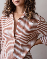 Woman wearing a brown and white striped shirt against a plain background