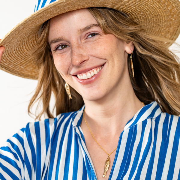 Woman wearing a straw hat and blue and white striped shirt on a white background