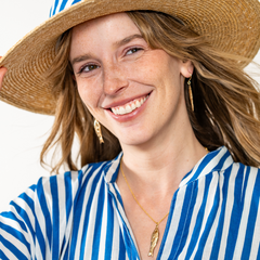 Woman wearing a straw hat and blue and white striped shirt on a white background
