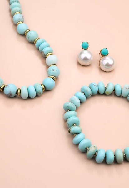 Turquoise beaded necklace, bracelet, and earrings on a beige background