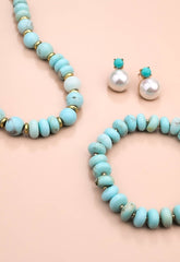 Turquoise beaded necklace, bracelet, and earrings on a beige background