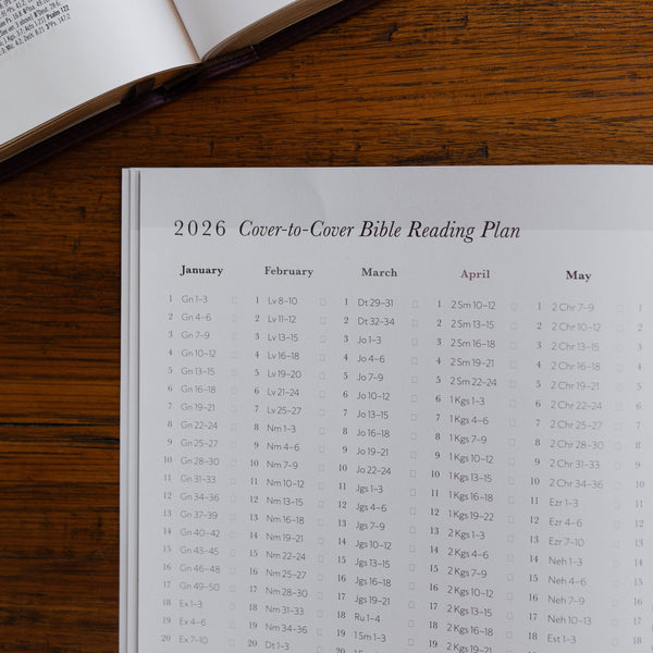 2026 Cover-to-Cover Bible Reading Plan on a wooden surface with an open book.