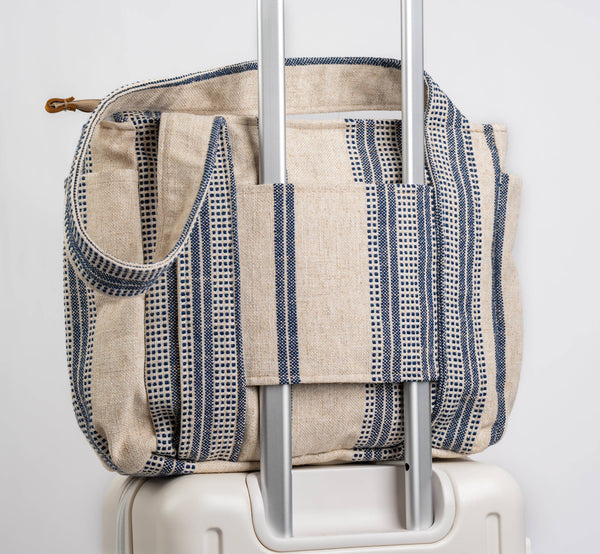 Striped fabric bag on top of a suitcase with a white background