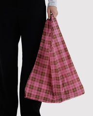Person holding a pink plaid bag against a white background