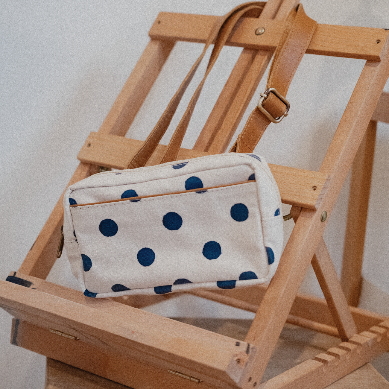 Polka dot pouch on a wooden chair with a neutral background