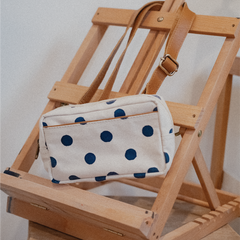 Polka dot pouch on a wooden chair with a neutral background