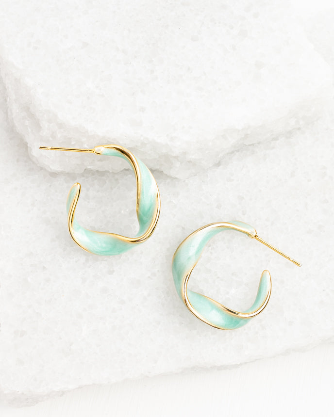 Pair of gold and light blue hoop earrings on a white marble surface