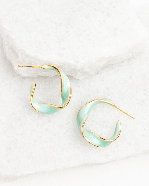 Pair of gold and light blue hoop earrings on a white marble surface