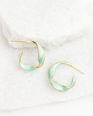 Pair of gold and light blue hoop earrings on a white marble surface