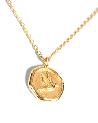 Close-up of a delicate gold chain necklace with an adjustable lobster clasp and a small leaf-shaped charm, photographed on a clean white background.