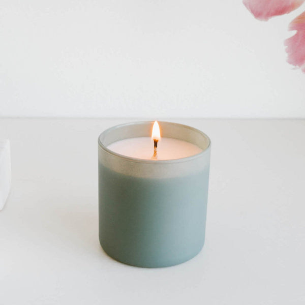 Candle in a light green container with a white background