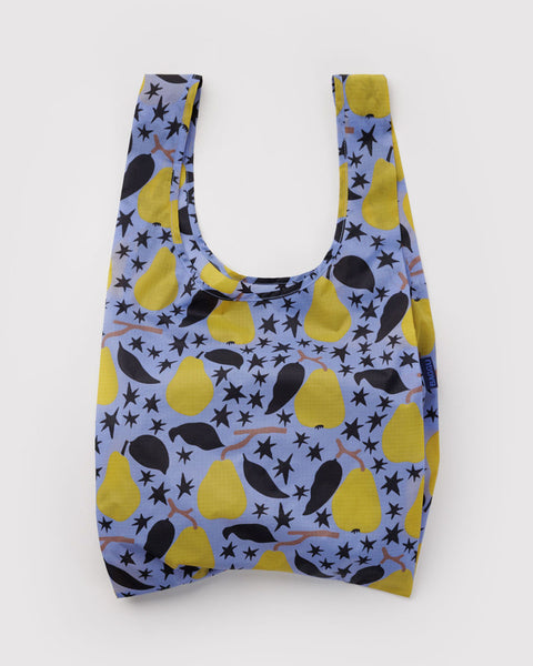A reusable fabric shopping bag with a pattern of yellow pears, black leaves, and black stars on a dusty blue background, shown against a plain light gray background.