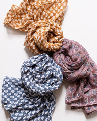Three patterned scarves in orange, blue, and pink on a white background