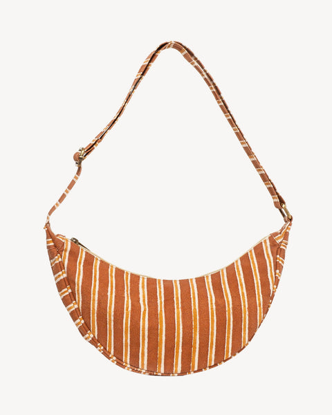 A crescent-shaped shoulder bag with a rust-orange and white vertical stripe pattern, featuring a matching adjustable strap, shown against a plain off-white background.