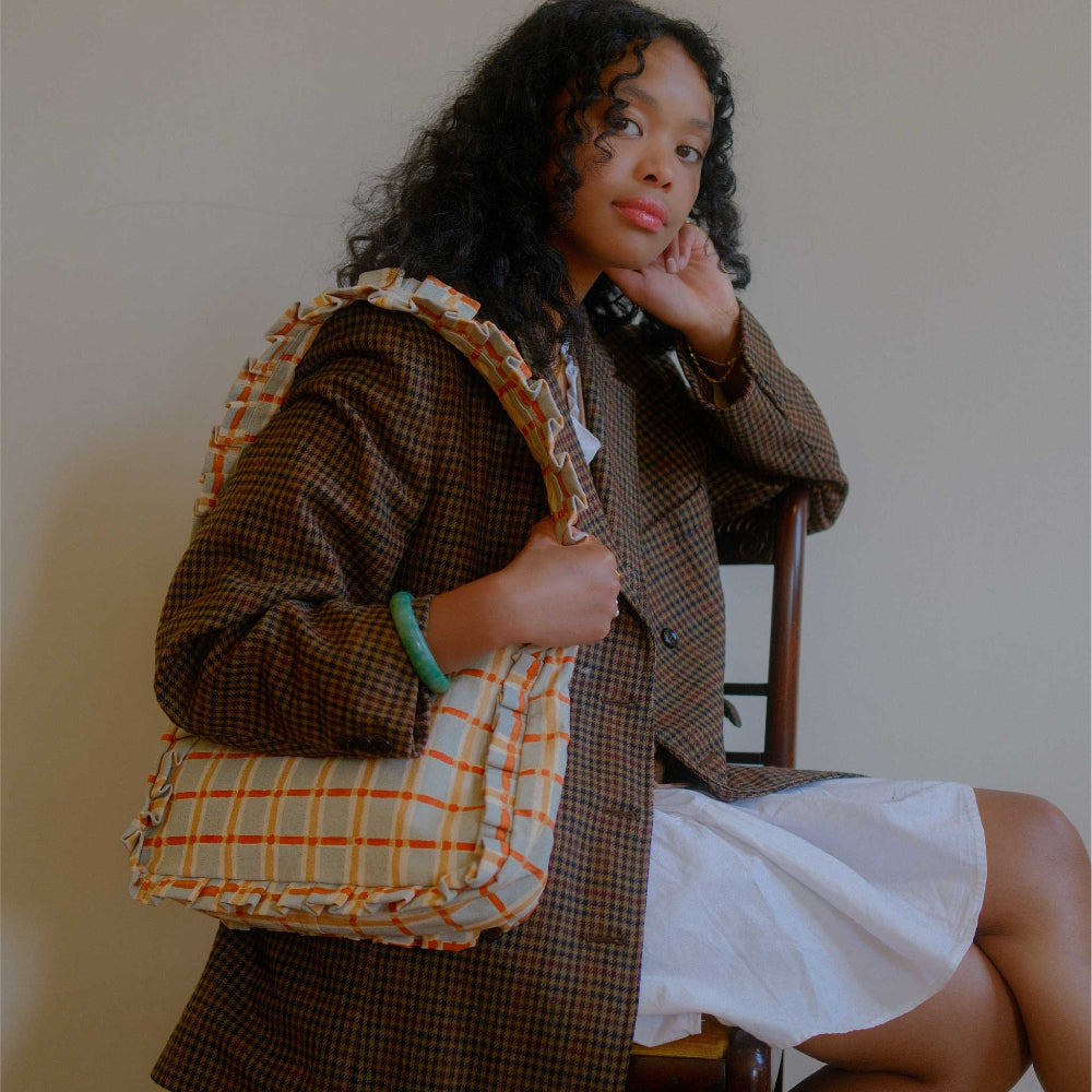 Woman holding a plaid bag against a plain background