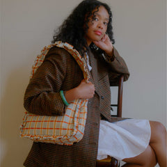 Woman holding a plaid bag against a plain background