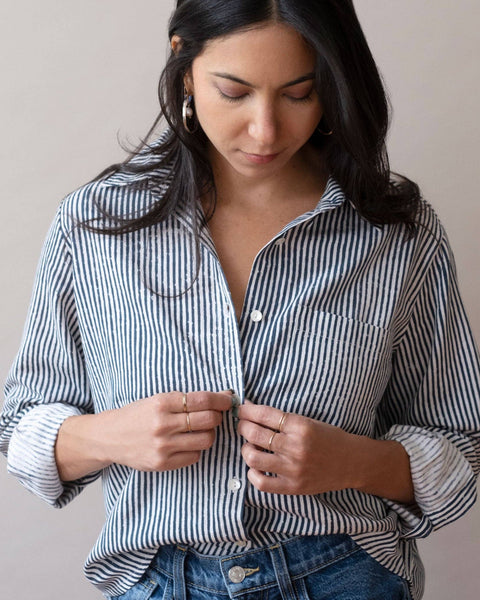 Woman wearing a navy and white striped shirt against a plain background