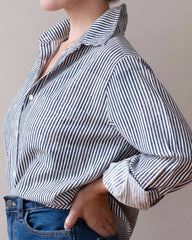 Person wearing a navy and white striped shirt with rolled-up sleeves against a plain background