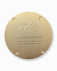 Gold circular coaster back with 'Paper Anchor Co.' branding and text on a white background