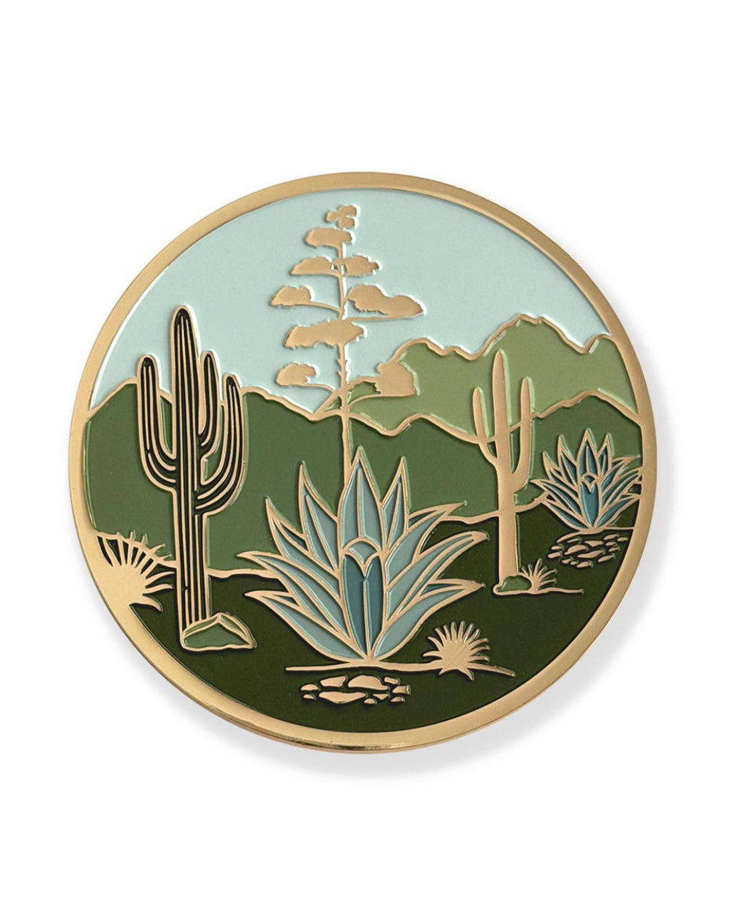 A circular desert landscape enamel coaster featuring saguaro cacti, agaves, mountains, and a light blue sky, with a gold-tone border on a white background.