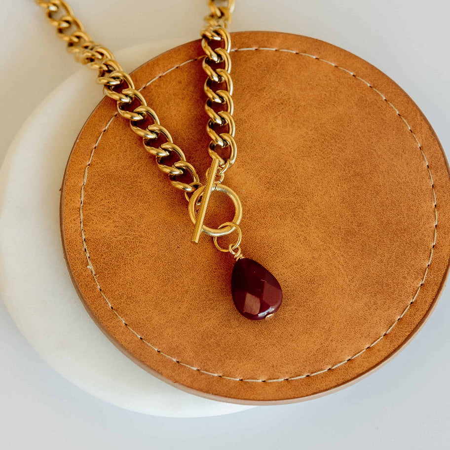 Gold chain necklace with a red teardrop pendant that fights trafficking 