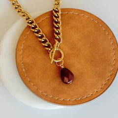 Gold chain necklace with a red teardrop pendant that fights trafficking 