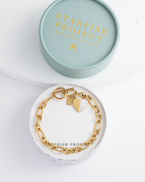 Gold bracelet with a tag in a 'Starfish Project' box on a white background