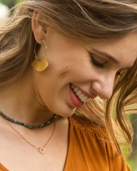 Woman wearing a necklace and earrings with a blurred natural background