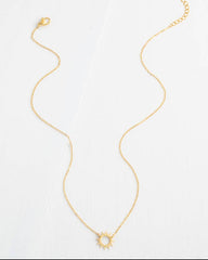 Gold necklace with a sun pendant on a white background